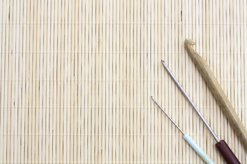 Crochet hooks on light makisu close-up, selective focus