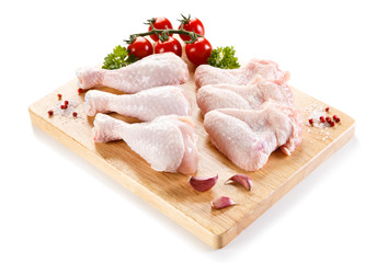 Raw chicken wings and drumsticks on cutting board on white background 