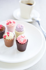 Small cup with heart shape chocolate on white plates
