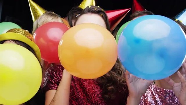 Multi racial group of friends blowing balloons slow motion party photo booth 