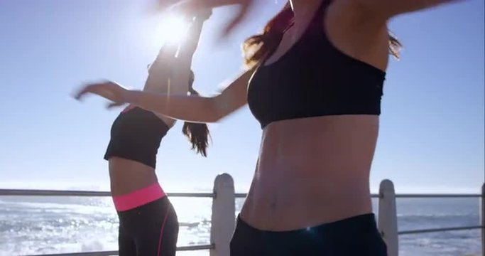 Two athletic friends stretching on promenade before run