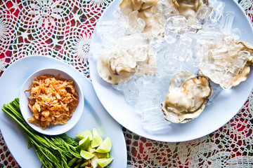 Oysters on ice serving with vegetables in Thai seafood restaurant