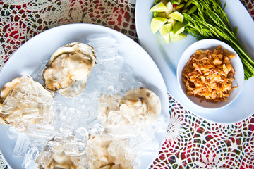 Oysters on ice serving with vegetables in Thai seafood restaurant