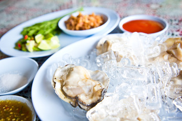 Oysters on ice serving with vegetables in Thai seafood restaurant