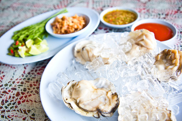 Oysters on ice serving with vegetables in Thai seafood restaurant