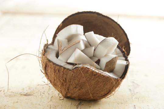 coconut half filled with coconut chunks on a wooden background