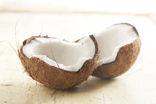 ripe coconut cut in half on a wooden background brightly lit.