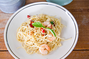 Chilli prawn spaghetti on wooden table in restaurant