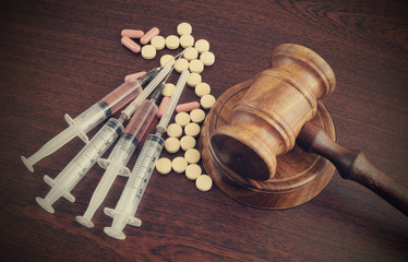 Narcotics concept, judge's gavel with drugs and syringes on wooden table