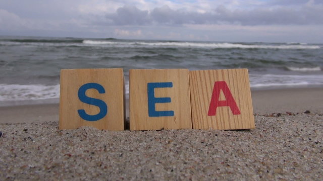 Word “sea” written with letter cubes on the beach