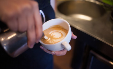 Fototapeta na wymiar Barista makes latte art, focus in milk and coffee, vintage color