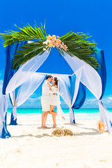 Wedding ceremony on a tropical beach in blue. Happy groom and br