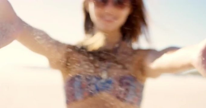 Close up of pretty girl  pouring sand running through fingers slow motion at the beach with sun flare and blue skye 