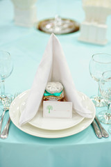 Beautiful holiday table setting in white and blue color with a gift on the plate