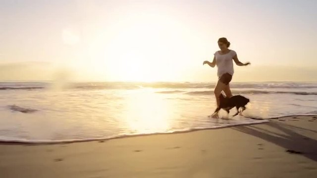 Woman running dog on beach lifestyle steadicam shot