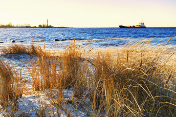 The ship enters the harbor lighthouse in winter