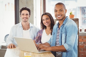 Portrait of smiling business people using laptop in office