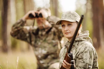 Papier Peint photo Chasser hunter with shotgun looking through binoculars in forest