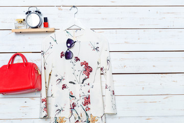 Modern woman's clothes hang on white wooden background