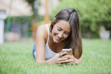 Young girl using cell phone while lying on grass