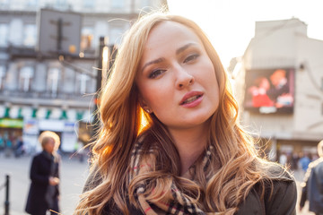 Beautiful blonde happy woman walking on the street in city. Outdoor photo.