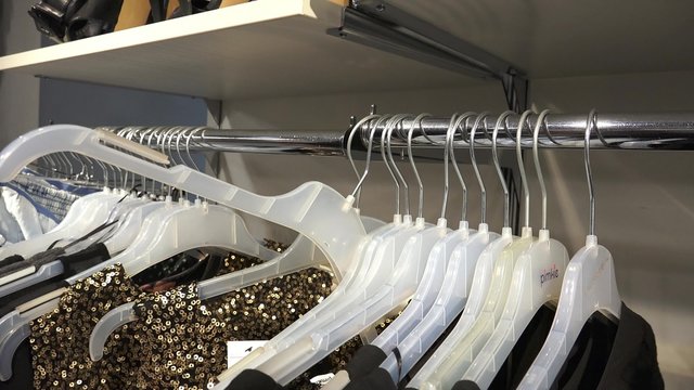 4k woman shopping in clothing store choosing on clothes hangers. UHD steadycam stock footage