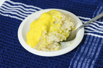 Mango sticky glutinous rice on a plate on a blue kitchen towel. A delicious asian thai cuisine dessert with cream, coconut milk and sugar (khao niao mamuang).