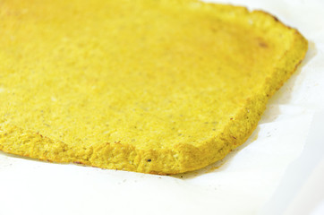 Cauliflower pizza crust. A healthy low carb, gluten free, vegan, vegetarian snack with grated cauli flower baked in the oven isolated on white background on parchment baking paper