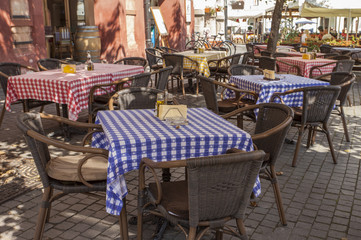 Fototapeta na wymiar restaurant summer terrace with table-cloth covered tables and wicker chairs