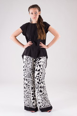 Attractive business woman with day make-up dressed white and black wide trousers with pattern and black blouse and high-heeled shoes for walks and meetings.