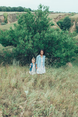 The young mother and daughter on green grass background 