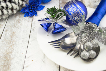 Christmas table setting in silver and blue tone on wooden table