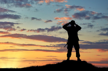 Silhouette of soldier looking through binoculars
