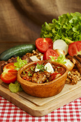 Stew in pot on wooden plank/Meat and vegetable in ceramic pot.Traditional domestic cuisine