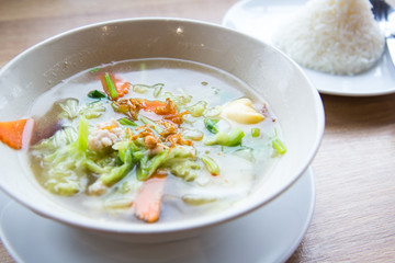 Traditional pork soup served in a white bowl over vegetable back