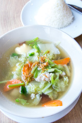Traditional pork soup served in a white bowl over vegetable back