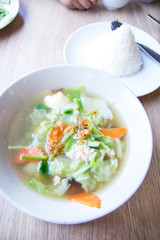 Traditional pork soup served in a white bowl over vegetable back