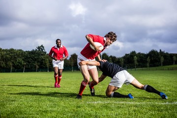 Rugby players tackling during game - obrazy, fototapety, plakaty