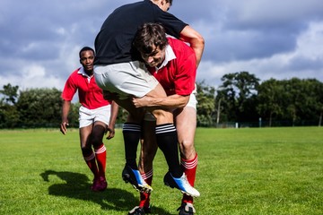 Naklejka premium Rugby players tackling during game