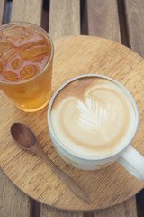 Cup of latte coffee with cold tea on wooden tray