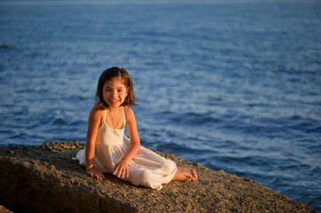 Милая девочка в белом платье на побережье моря