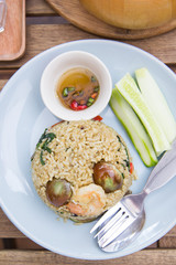 Spicy green curry fired rice with shrimps on wooden table