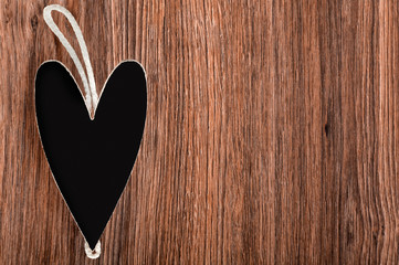 black wooden heart with rope to a wooden background