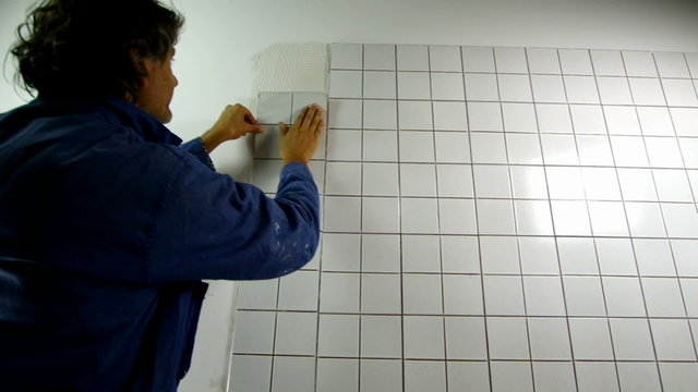 Worker distributes the mass of the tile glue cement with trowel