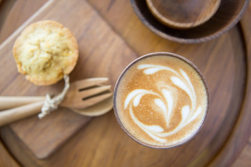 Latte art coffee on wooden cup with pumpkin muffin
