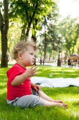 small child sits on the grass in the Park