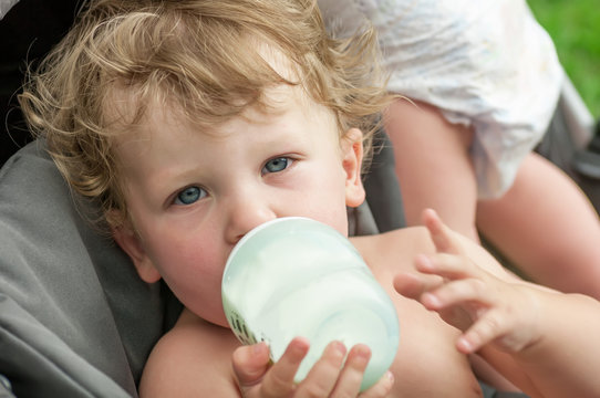baby sucking on a bottle of porridge sitting in a wheelchair
