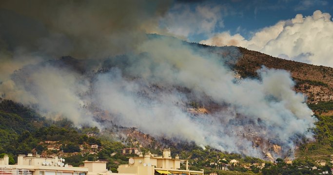 The fire on the slopes of the mountains on the border of France and Italy, Menton and Ventimiglia, burning houses and the forest, a lot of smoke, fire extinguish aircraft