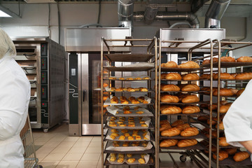Racks of fresh loaves of bread and buns from ovens in Bakery