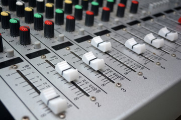 Detail of a music mixer desk with various knobs or slides. shallow depth of field
